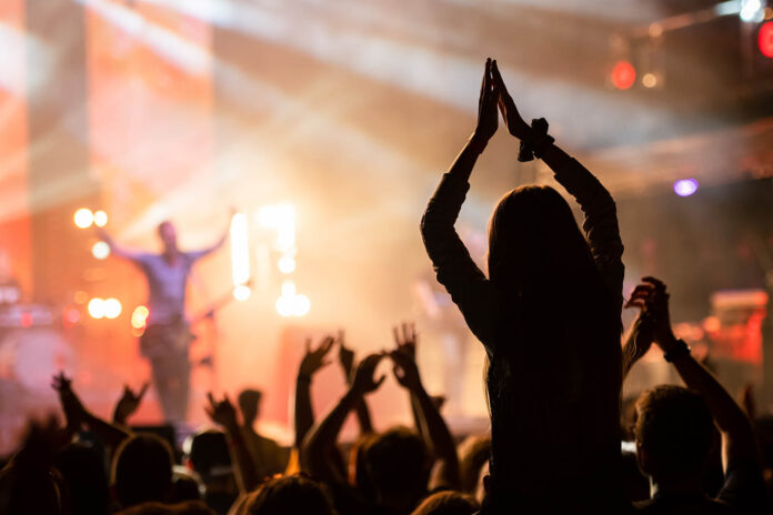 concerto dal vivo Bologna marzo 2026, palco con cantante e folla che batte le mani