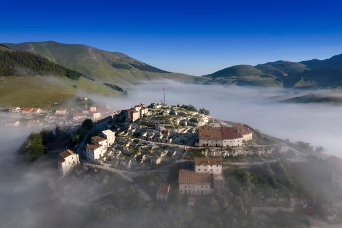 Piani di Castelluccio in fioritura con strisce di papaveri rossi e fiordalisi azzurri sul Pian Grande in Umbria